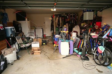 The inside of a garage with no room for the car, thanks to the clutter on the floor!